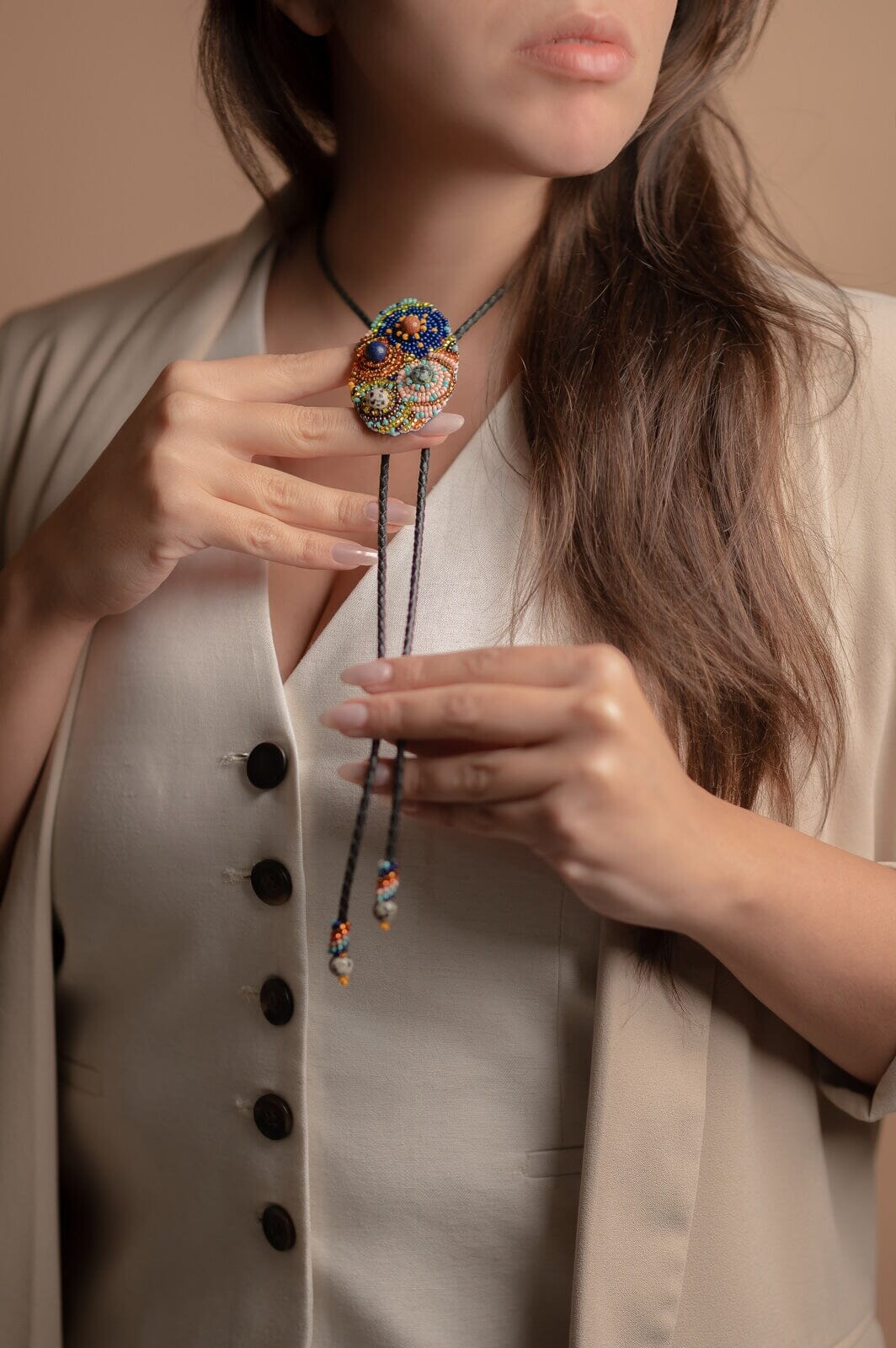 woman wearing bourbon cowgirl Bolo Tie blue red gold pink textured beaded necklace beaded native american jewelry mexico guatemala handmade accessory aglets slide clasp 